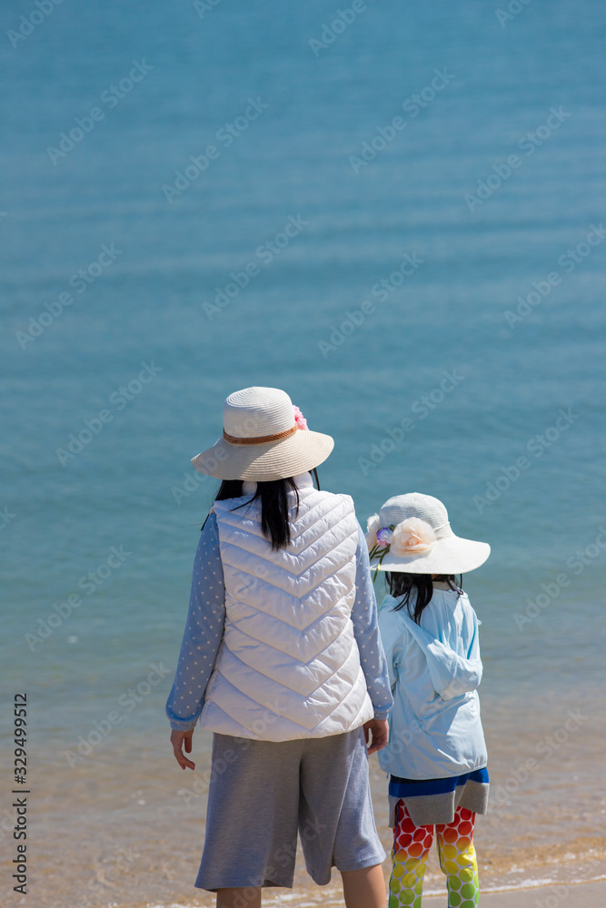 初夏の海の砂浜で遊んでいる子供姉妹