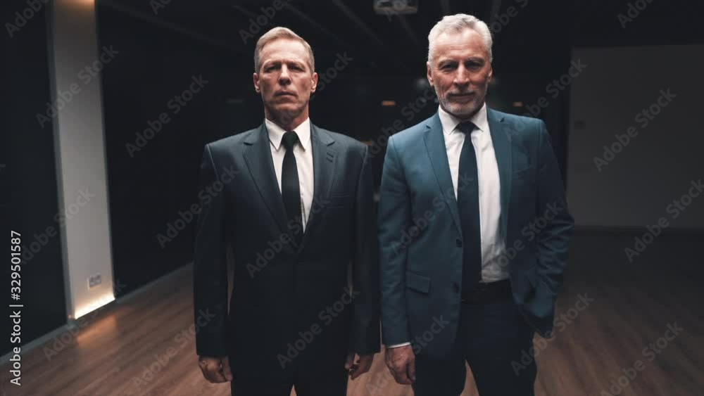The two businessmen in suits posing on camera. slow motion The two businessmen in suits posing on camera. slow motion