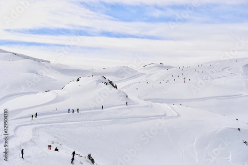 Ski slope with skiing people by winter 