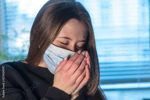 Prevent the spread of the Coronavirus Disease 2019 (COVID-19). Young woman sneezing or coughing in a protective medical face mask 