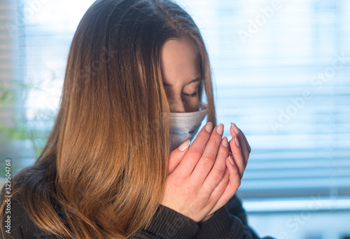 Prevent the spread of the Coronavirus Disease 2019 (COVID-19). Young woman sneezing or coughing in a protective medical face mask 