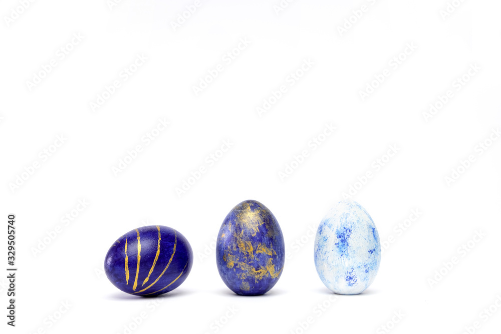 Three easter eggs trendy colored classic blue, white and golden decorated on white table. Happy Easter card with copy space for text. Minimal style. Three easter eggs trendy colored classic blue, white and golden decorated on white table. Happy Easter card with copy space for text. Minimal style.