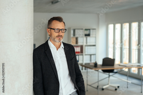 Foto Businessman standing leaning against a wall