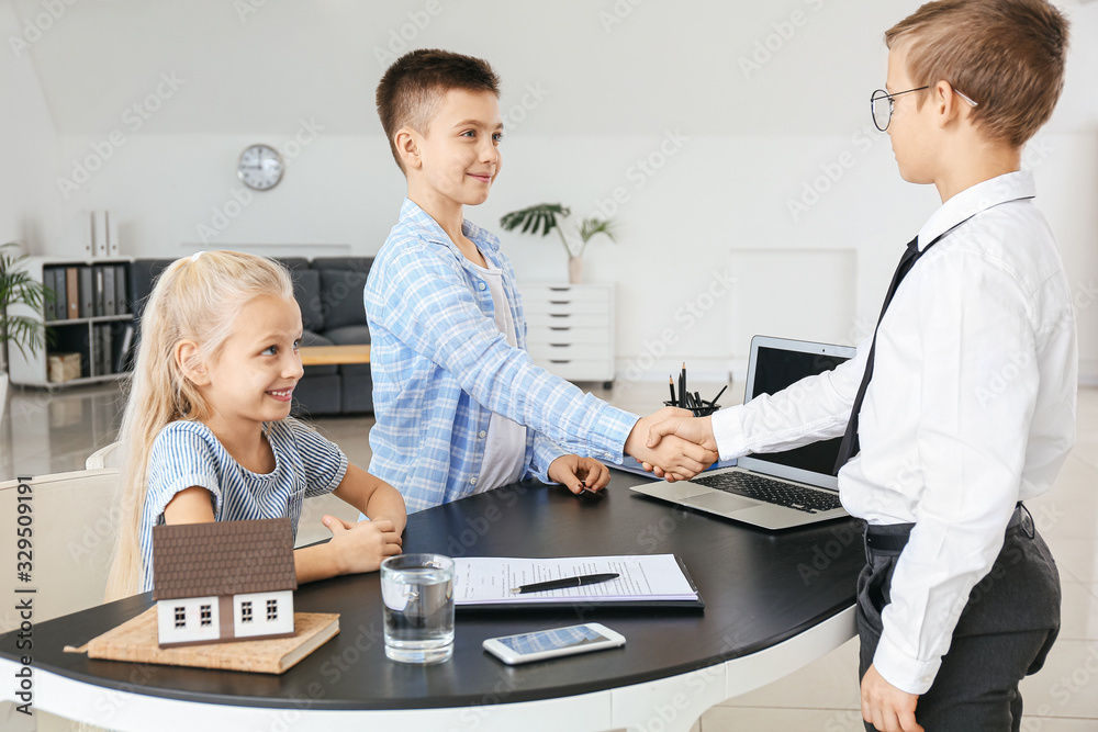 Little real estate agent with clients shaking hands in office