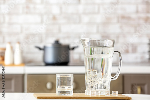фотографія Glass and jug of cold clean water on table in kitchen