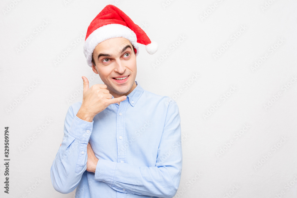 Guy in Santa Claus hat shows the hand gesture  call me up, portrait, white background