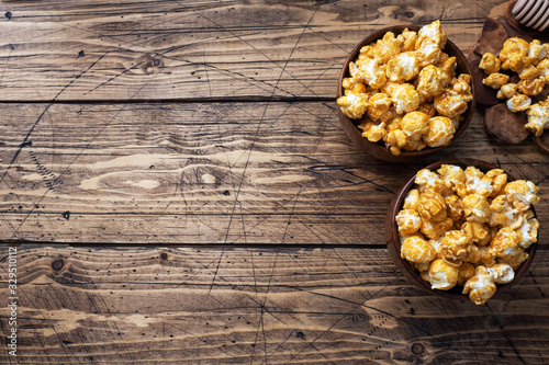 Popcorn in caramel glaze in wooden plates on a rustic table. Copy space.