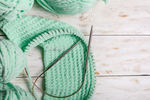 Wicker basket with turquoise thread for knitting and knitting needles. Azure plaid and knitting yarn closeup