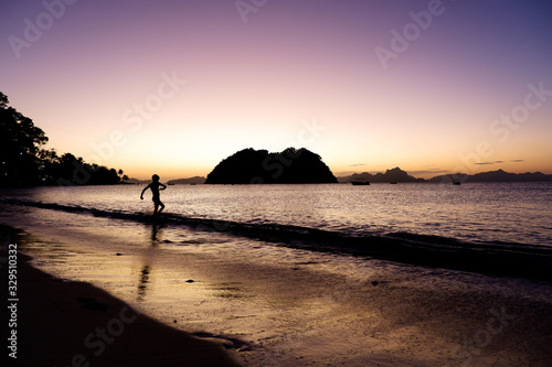 Kid playing with waves. Glowing sunset in El Nido, Palawan, Philippines