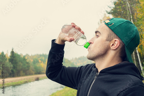 Concept of sports, training and active lifestyle. Handsome man with a bottle of water, close up