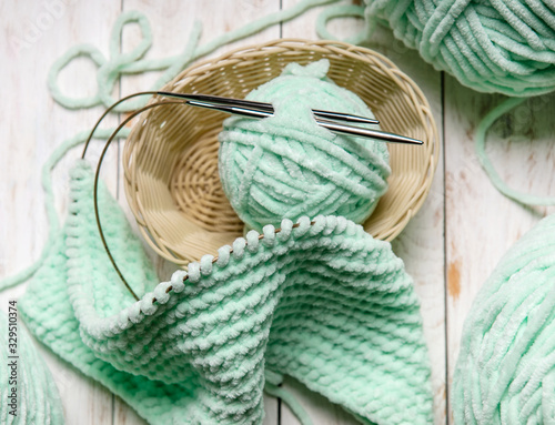 home hobbies, cozy knitted plaid with a ball of yarn in the living room on white wooden background