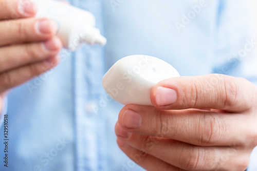 Man holding blank white squeeze bottle plastic tube, closeup, copy space