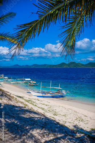 Blue boat on white sand beach. Black island, Coron, Philippines