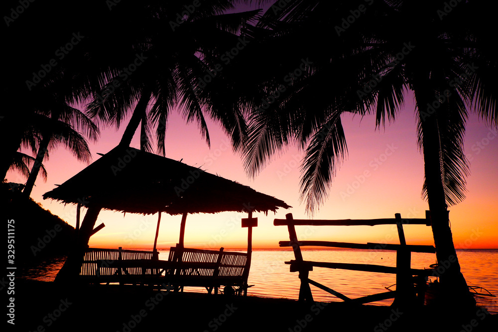 Silhouettes of bamboo hut and bench. Glowing sunset, Coron island, Philippines.