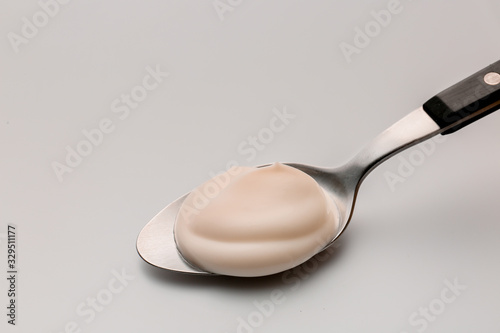 Spoon with fresh yogurt on white background photo