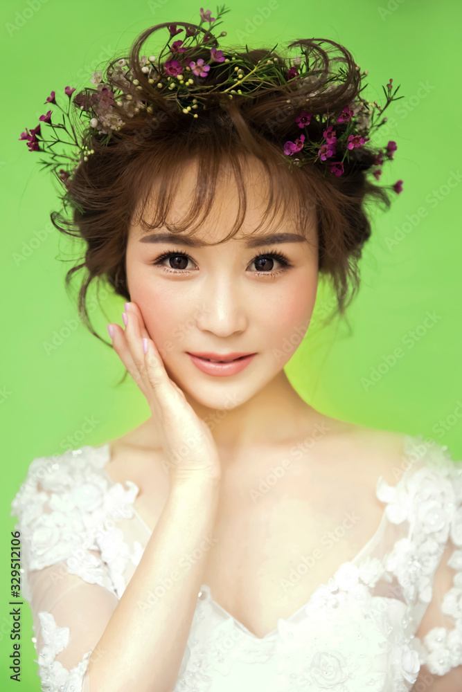 Asian girl wearing flowers headdress in green background Asian girl wearing flowers headdress in green background