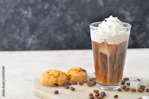 Glass of tasty iced coffee and cookies on table