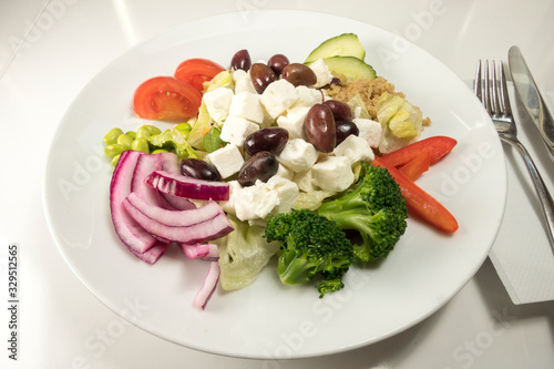 A Greek salad with feta cheese and broccoli, onions and olives.