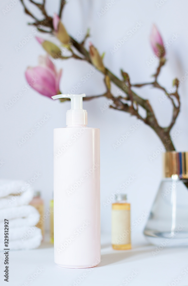 Cleansing cosmetic product in the bathroom with magnolia flower branch. Antibacterial soap in a plastic tube ob the white background close up Cleansing cosmetic product in the bathroom with magnolia flower branch. Antibacterial soap in a plastic tube ob the white background close up