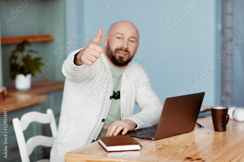 Portrait of a man working on a laptop and making the OK gesture.