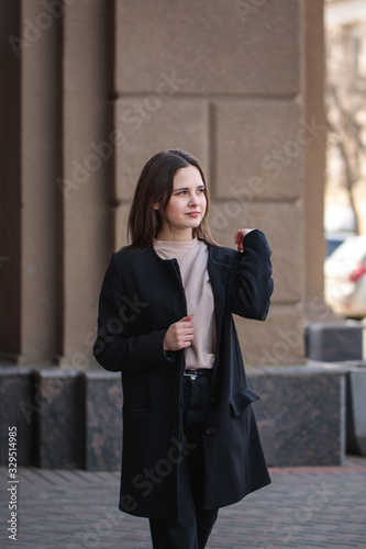 Portrait of a young woman walking around the city and looking around. Beautiful stylish woman walks along the street.