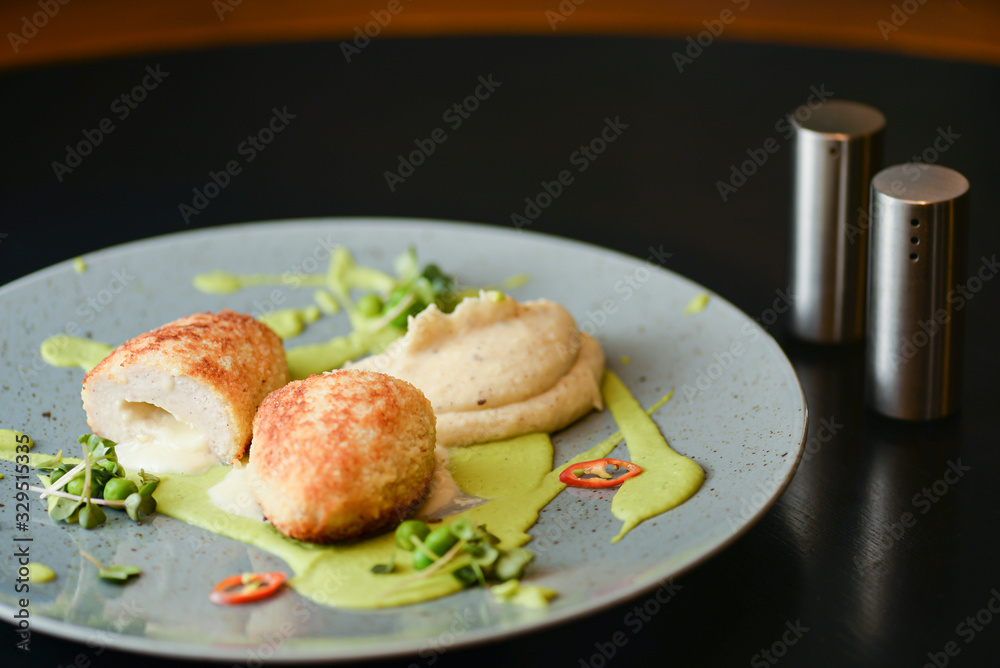 Cordon bleu chicken cutlet. Keiv cutlet with gravy and sauce served on a blue plate on dark rustic wooden table. Cordon bleu chicken cutlet. Keiv cutlet with gravy and sauce served on a blue plate on dark rustic wooden table.