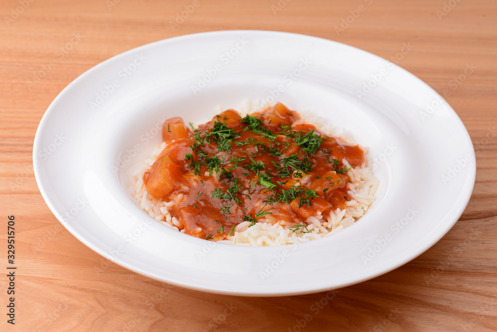 Rice with beef stew with green beans and vegetables served in white plate over light rustic wooden table. Rice with beef stew with green beans and vegetables served in white plate over light rustic wooden table.
