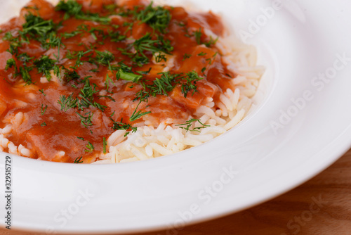 Rice with beef stew with green beans and vegetables served in white plate over light rustic wooden table.