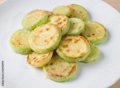 Fried young zucchini on a white plate. Close-up