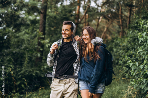 Young couple with backpacks on their backs smiling and walking in the forest, enjoy the walk