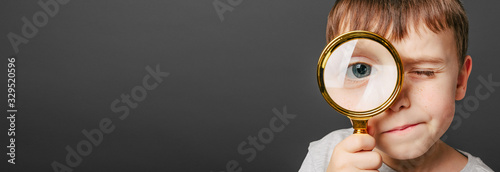 Child see through magnifying glass on the black backgrounds. photo