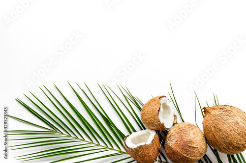 Exotic background with coconuts and palm leaves on white background top-down frame copy space