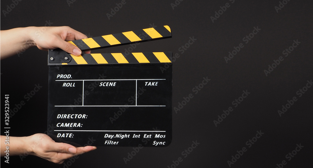 Hand is holding black clapper board or movie slate.It is used in video production and film industry on black background.