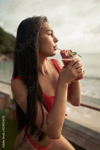 Beautiful young woman drink fruit shake and having fun at cocktail bar on the beach while sunset
