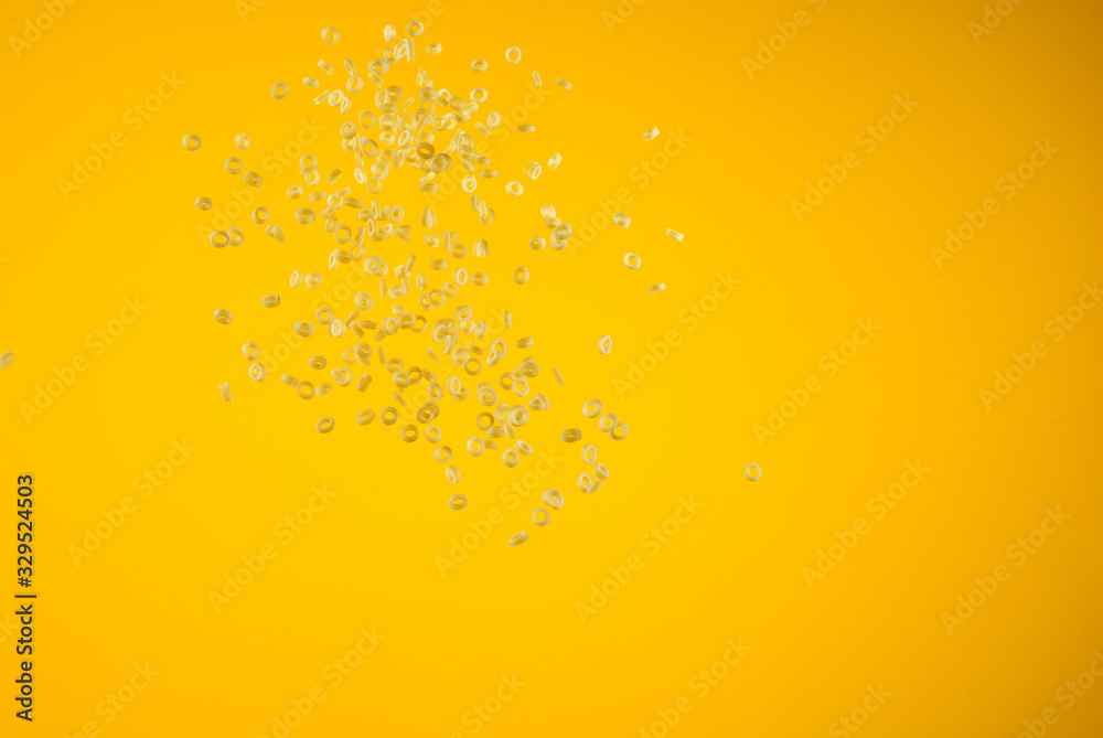 Freeze motion of flying uncooked pasta on yellow background, food concept.