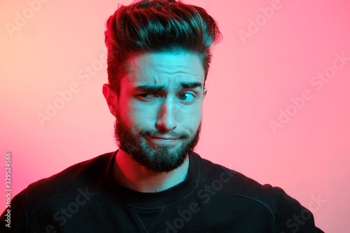 Beautiful caucasian young man portrait isolated on multicolored neon light backgroud. Young, smiling, surprised, screaming. Human emotions, facial expression concept. Trendy colors.Advertising concept