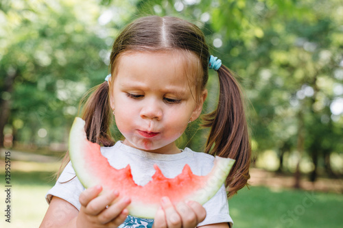 Cute child eating ripe watermelon in garden