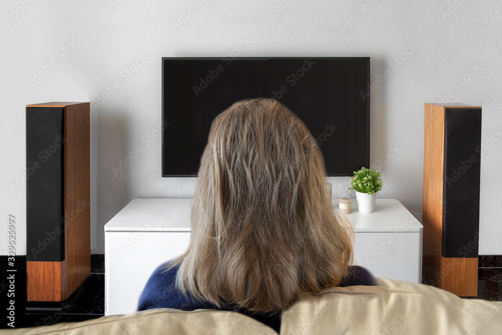 Unrecognised woman watching television at home. Smart tv and home cinema concept Unrecognised woman watching television at home. Smart tv and home cinema concept