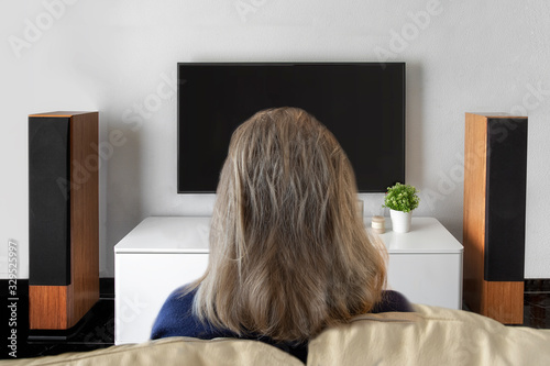 Unrecognised woman watching television at home. Smart tv and home cinema concept