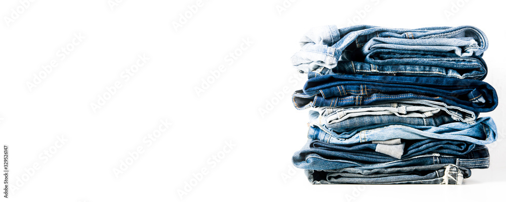 A stack of old jeans isolated on a light background A stack of old jeans isolated on a light background
