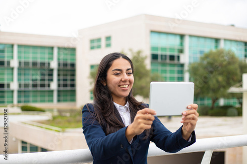 Content young woman using tablet pc. Cheerful young businesswoman having video chat via digital tablet in urban city. Communication concept