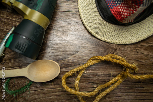 Hat, binoculars, wooden spoon, fishing line, on wooden background