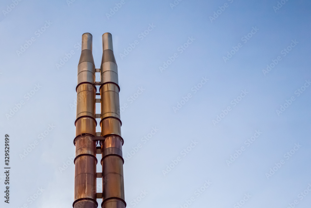 Two rusty pipes against the blue sky.