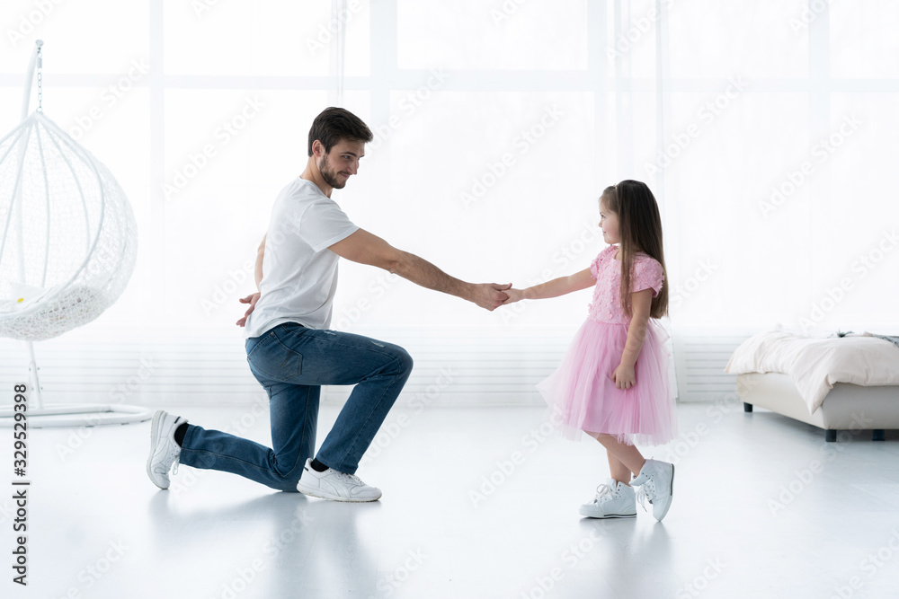 Fototapeta premium I love you, dad! Handsome young man is dancing at home with his little girl. Happy Father's Day!