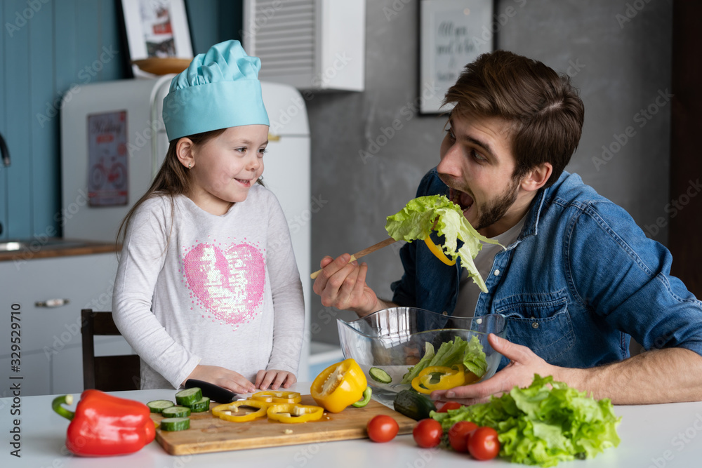 Handsome man and his little cute daughter are cooking on kitchen. Making salad. Healthy lifestyle concept. Handsome man and his little cute daughter are cooking on kitchen. Making salad. Healthy lifestyle concept.