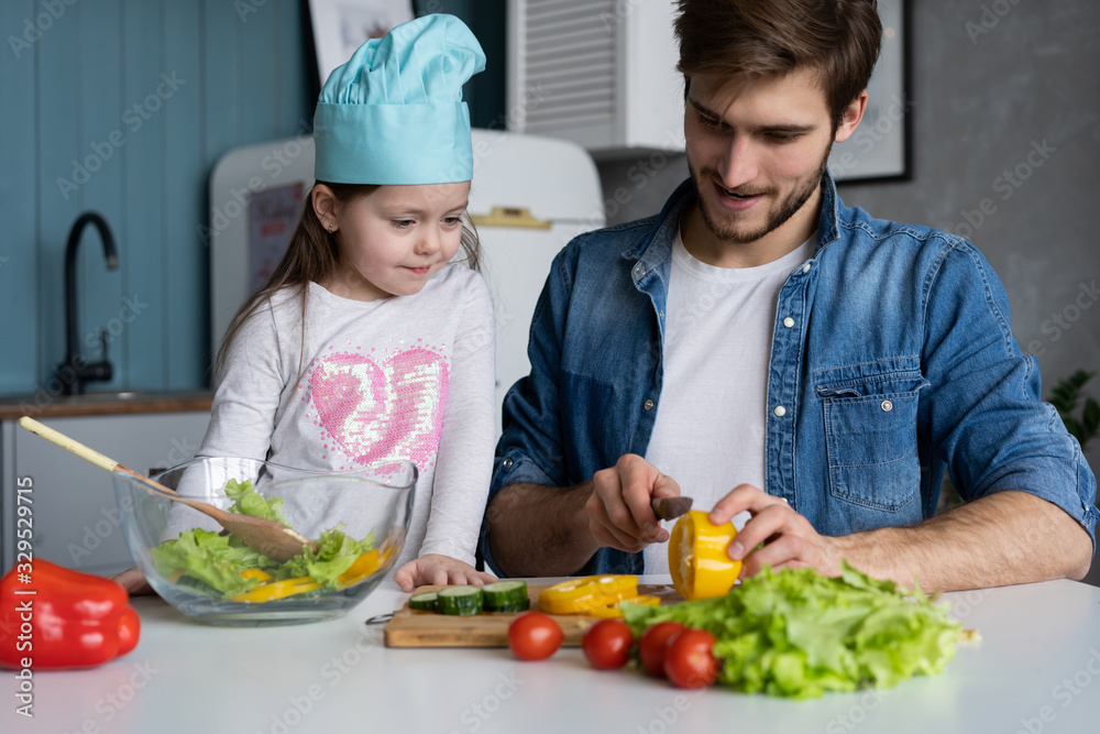 Handsome man and his little cute daughter are cooking on kitchen. Making salad. Healthy lifestyle concept. Handsome man and his little cute daughter are cooking on kitchen. Making salad. Healthy lifestyle concept.