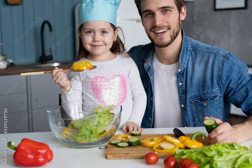 Handsome man and his little cute daughter are cooking on kitchen. Making salad. Healthy lifestyle concept. Handsome man and his little cute daughter are cooking on kitchen. Making salad. Healthy lifestyle concept.