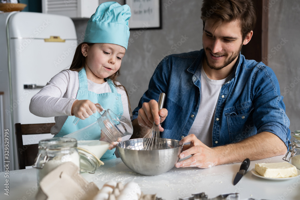 Daddy with daughter baking cake together in home kitchen. Daddy with daughter baking cake together in home kitchen.