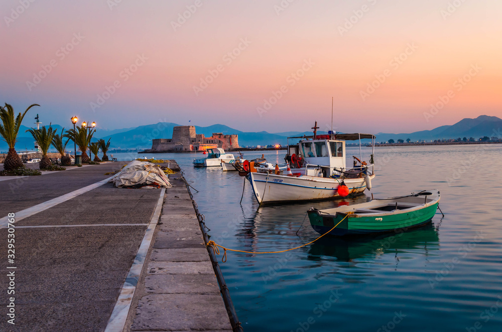 Nafplio Greece- View of the beautiful port of Nafplio with small boats and the castle of Bourtzi at sunset.