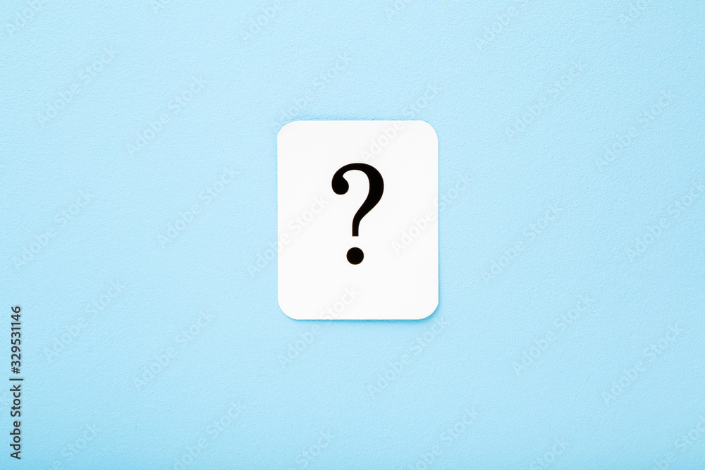 White card of question mark on light blue background. Pastel color. Top down view. Closeup. White card of question mark on light blue background. Pastel color. Top down view. Closeup.